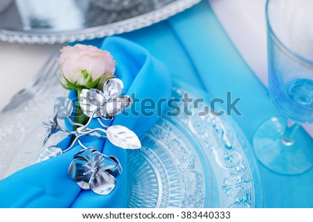 Wedding accessories in blue colors. Luxury wedding lunch table setting outdoors, in white-blue colors.  Beautiful holiday table setting in white and blue color with a gift on the plate.