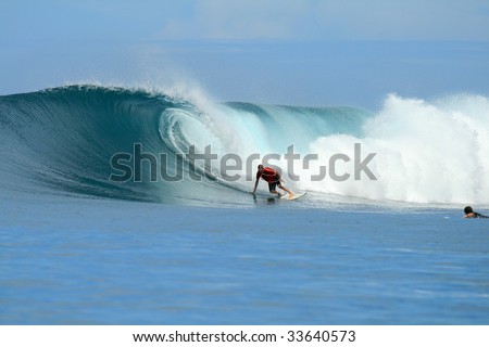 Blonde surfer in orange shirt on big wave, Mentawai Islands, Indonesia