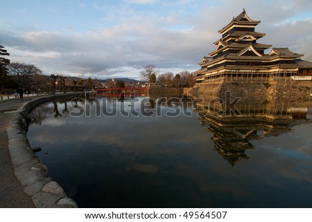 Matsumoto Castle with foreground showing reflection of castle, sky and bridge in the water