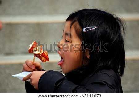 MT. FUJI, JAPAN - MARCH 28 : Little girl tastes the local specialty made of octopus on March 28, 2008 in Mt. Fuji, Japan. Mt. Fuji, the symbol of Japan is a draw for Japanese people for a weekend.