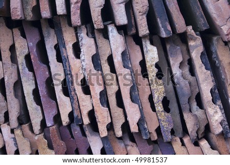 Victorian roof tiles stacked on end in warm multi coloured shades of terracotta