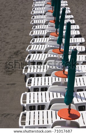 White deckchairs and green umbrellas waiting for the holiday makers