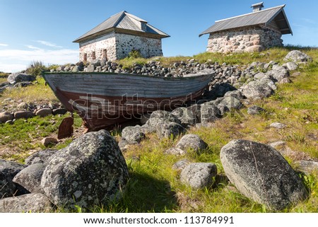 Old boat and stone houses on the shore. Bolshoi Zayatsky Island, Solovetsky Islands, The White Sea, Karelia, Russia.