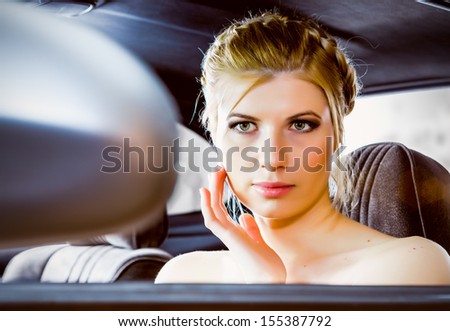 An attractive woman looks at herself in the driving mirror