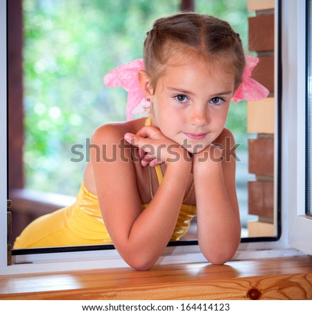 A portrait of a six years\' girl  in the window in the afternoon.
