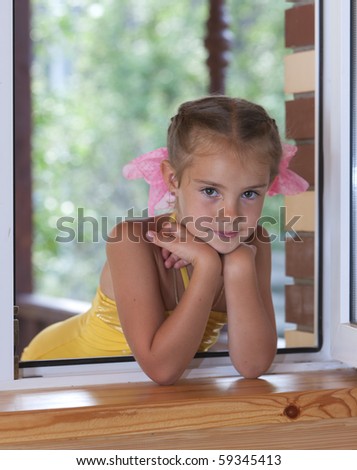 A portrait of a six-year girl  in the window in the afternoon.