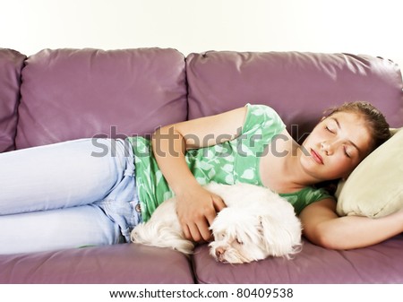 Teenage girl and her dog sleeping together on a sofa