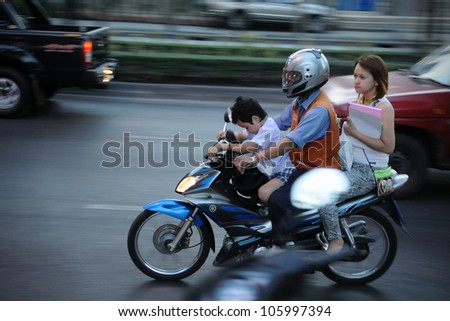 BANGKOK - JAN 11: A motorbike taxi transports passengers on a busy road on Jan 11, 2011 in Bangkok, Thailand. Motorbike taxis can be hired from as little as $0.30 or B10 a fare for short trips.