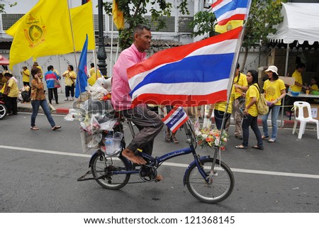 BANGKOK - DEC 5: A man rides a bicycle decorated with Thai and royal flags while attending celebrations of Thai King Bhumibol\'s 85th birthday on the Royal Plaza on Dec 5, 2012 in Bangkok, Thailand.