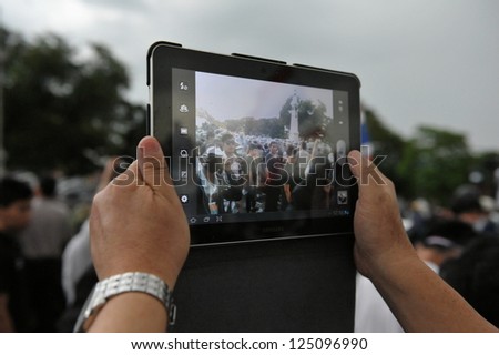 BANGKOK - NOV 24: A protesters uses a tablet computer to photograph an anti-government rally organised by the nationalist Pitak Siam group on Nov 24, 2012 in Bangkok, Thailand.