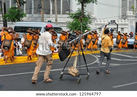 BANGKOK - JAN 25: A film crew use a DSLR mounted on a mobile rig to film Buddhist monks making a pilgrimage through central Bangkok on Jan 25, 2013 in Bangkok, Thailand.