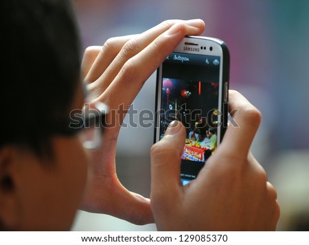 YANGON - FEB 10: A temple-goer uses a smartphone to share a photo via Instagram at a temple ceremony during festivities ushering in the Chinese new year of the snake on Feb 10, 2013 in Yangon, Burma.