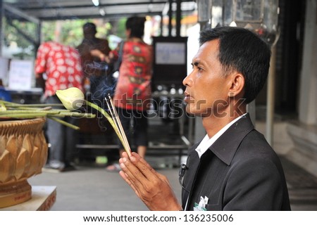 BANGKOK - APRIL 12: An unidentified man prays while taking part in a merit making ceremony at a Buddhist temple during Songkran, or Thai New Year, celebrations on April 12, 2013 in Bangkok, Thailand.