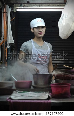 BANGKOK - DEC 13:An unidentified street vendor cooks at a night market on Dec 13, 2012 in Bangkok, Thailand. According government statistics there are over 16,000 registered street vendors in Bangkok.