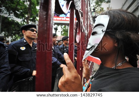BANGKOK - JUNE 16: A protester wearing a Guy Fawkes mask shouts slogans at riot police outside the Royal Thai Police headquarters during a anti-government rally on June 16, 2013 in Bangkok, Thailand.