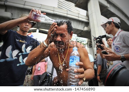 BANGKOK - JULY 21: A protester washes away an unidentified tear gas like chemical after coming under attack during an anti-government rally on July 21, 2013 in Bangkok, Thailand.