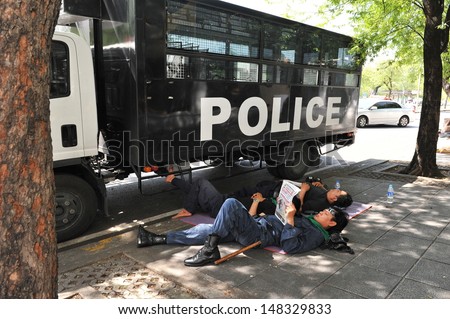 BANGKOK - AUG 1: Police rest outside Government House as the government invokes martial law amid threats to national security and planned anti-government rallies on Aug 1, 2013 in Bangkok, Thailand.