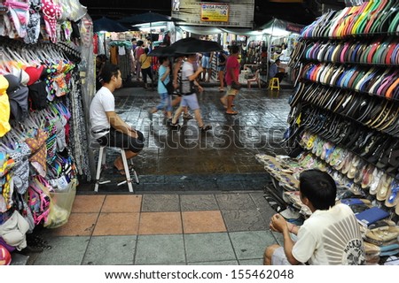BANGKOK - SEP 10: Tourists walk past a market store on Khao San Road on Sep 10, 2013 in Bangkok, Thailand. Khao San market is a popular tourist attraction known for its budget and counterefeit goods.