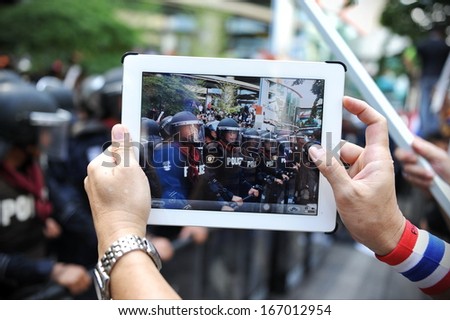 Bangkok - Nov 29: An Anti-Government Protesters Uses A Tablet Device To Capture A Police Line At A Large Rally Outside The Ruling Pheu Thai Party\'S Headquarters On Nov 29, 2013 In Bangkok, Thailand.