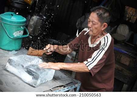 BANGKOK - NOV 2: An unidentified vendor cuts ice at a street-side restaurant on Nov 2, 2011 in Bangkok, Thailand. Government statistics show 16000 registered street vendors in the Thai capital.