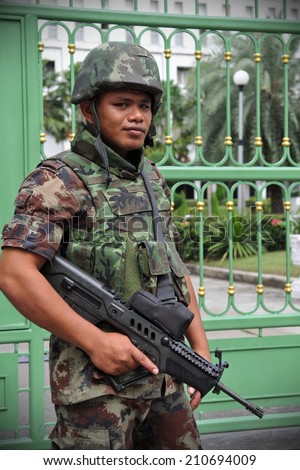 BANGKOK - JUN 26: An unidentified armed Thai soldiers stands guard outside a military installation as anti election protesters hold a rally nearby on Jun 26, 2011 in Bangkok, Thailand.