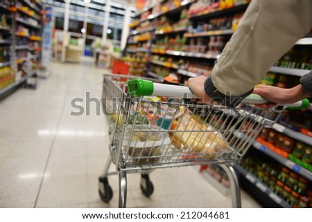 Supermarket Aisle View of a Shopping Trolley and Shelves - Image has a Shallow Depth of Field