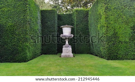 View of a Lush Lawn, Ornamental Stone Vase and Sculpted Hedge Topiary in a Beautiful Formal Garden
