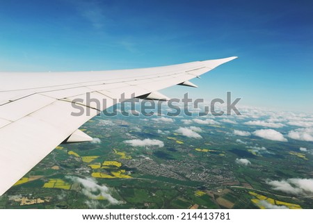 View from an Airplane Window of a Wing, Sky and Land