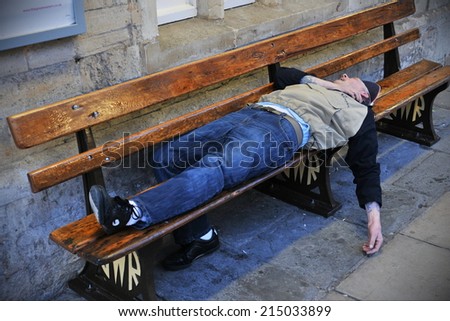 BRADFORD ON AVON - APR 9: An unidentified man sleeps on a train station bench on Apr 9, 2011 in Bradford on Avon, UK. The government estimates around 2000 people sleep rough in England on any one day.