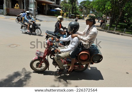 SIEM REAP - JUL 11: Workers carry canisters by motorbike on Jul 11, 2012 in Siem Reap, Cambodia. Goods are often carried by motorbike in poverty stricken Cambodia, where over 20% live on $1 a day.