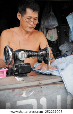 BANGKOK - JAN 20: A man operates a sewing machine in a street side garments factory shop on Jan 20, 2011 in Bangkok, Thailand. Textiles and clothing is Thailand\'s largest manufacturing industry.