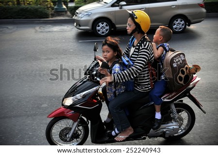 BANGKOK - JAN 14: A family make school run by motorbike on a busy city centre road on Jan 14, 2011 in Bangkok, Thailand. The use of motorbikes as family transport is commonplace in Thailand.