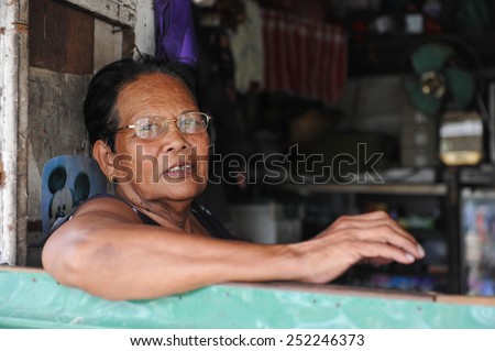 BANGKOK - JAN 20: A woman looks-on from a window in one of the Thai capital\'s shanty town on Jan 20, 2011 in Bangkok, Thailand. Bangkok has many shanty towns despite limited social housing projects.