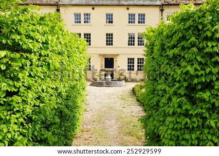 Scenic View of a Hedge Lined Path Leading to a Beautiful Victorian Era English Country House