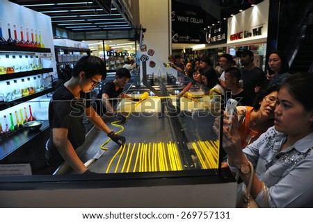 BANGKOK - AUG 28: Customers watch and wait as staff at a confectionery store make candy on Aug 28, 2013 in Bangkok, Thailand. The Thai capital is famous for its wide variety of foods and desserts.