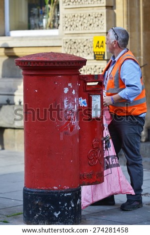 BATH - APR 28: A postman collects mail from a postbox on a city centre street on Apr 28, 2015 in Bath, UK. Britain\'s public postal service is one of the oldest in the world.