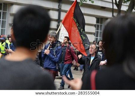 LONDON - MAY 30: Foreign tourists look-on as protesters rally against public sector spending cuts following the re-election of the Conservative party on May 30, 2015 in London, UK.