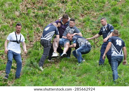 BROCKWORTH - MAY 25: Revelers help an injured competitor in the traditional cheese rolling races on May 25, 2015 in Brockworth, UK. Thousands attended the unofficial annual event which dates to 1800s.