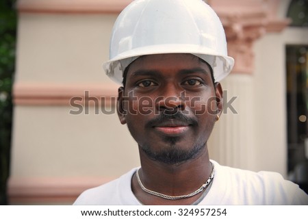 SINGAPORE - MAY 10: A migrant worker poses for a photo on a city centre construction site on May 10, 2013 in Singapore. The SE Asian city state has a significant migrant worker population.