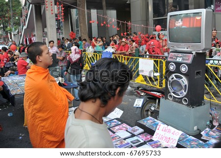 BANGKOK - DEC 19: A monk watches a video of a speech given by assassinated army general Seh Daeng during a 10,000 strong anti government rally at Rachaprasong on Dec 19, 2010 in Bangkok, Thailand.