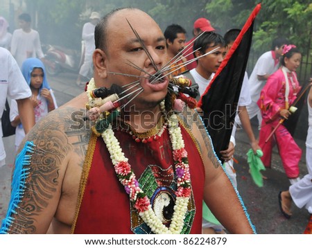 PHUKET - OCT 3: A Taoist spirit medium with his cheeks pierced with Chinese God idol skewers participates in a procession marking the Phuket Vegetarian Festival on Oct 3, 2011 in Phuket, Thailand.