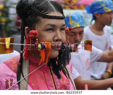 PHUKET - OCT 3: A Taoist spirit medium with cheeks pierced with needles participates in a procession during the Phuket Vegetarian Festival on Oct 3, 2011 in Phuket, Thailand.