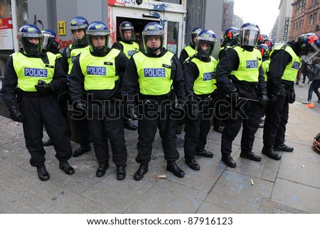 LONDON - MARCH 26: Riot police stand guard outside a branch of HSBC after the bank comes under attack by a breakaway group of protesters during a large anti-cuts rally on March 26, 2011 in London, UK.