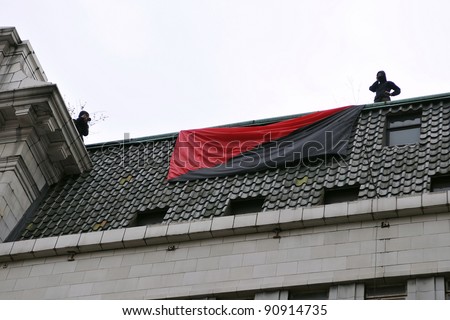 LONDON - MARCH 26: Anarchist protesters unveil a flag and occupy a building in central London during a large anti-cuts protest on March 26, 2011 in London, UK.