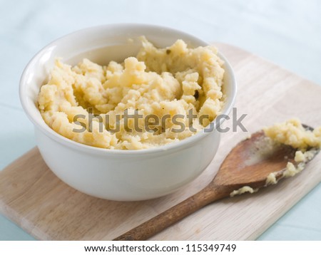 Mashed potato with wooden spoon in serving bowl, selective focus