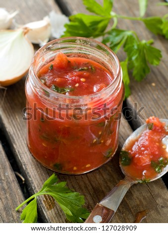 Tomato sauce (jam) with pepper, parsley and garlic in glass jar, selective focus, shallow doff