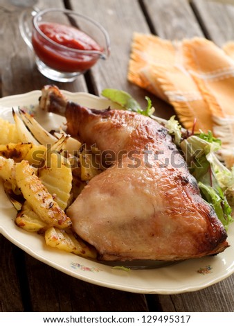 Roasted chicken leg with fried potato and salad, selective focus