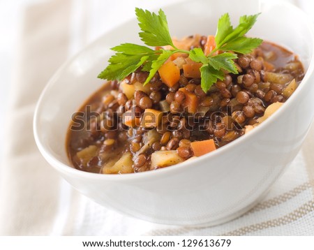 Brown lentil stew in bowl with vegetable, selective focus