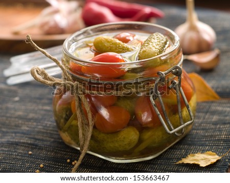 Preserved cucumber and tomato in glass jar, selective focus
