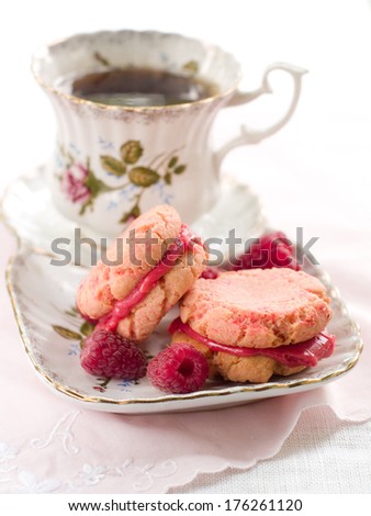 Cup of tea and cookies with raspberry cream, selective focus